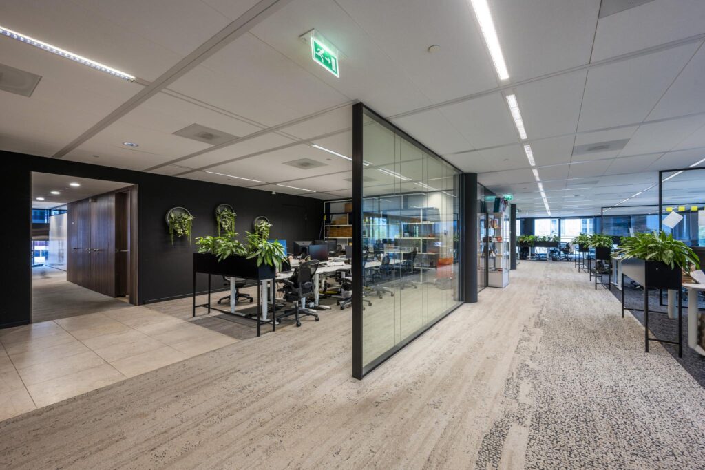 Modern office interior on Gustav Mahlerlaan with glass walls, open workspaces, and greenery throughout.